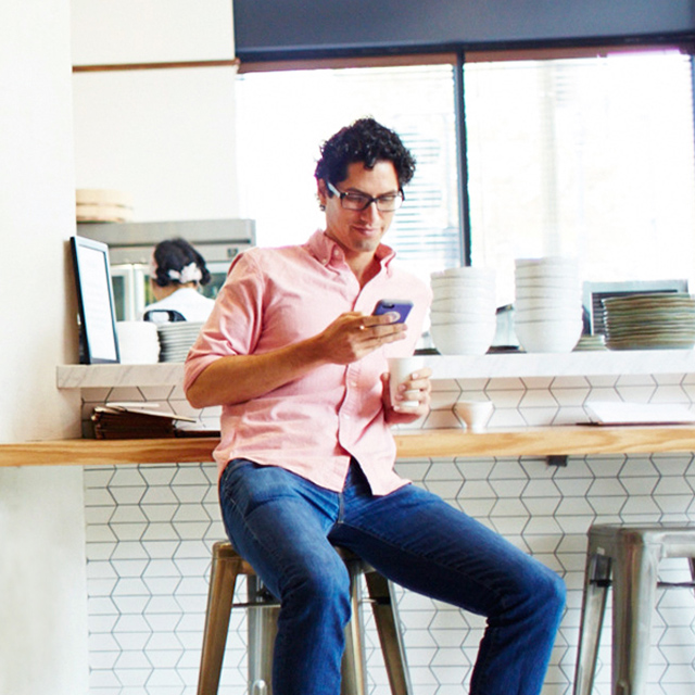 Man seated at café counter checking his phone.