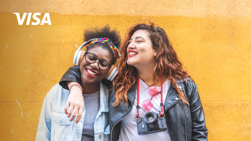 Two women posing in front of yellow wall