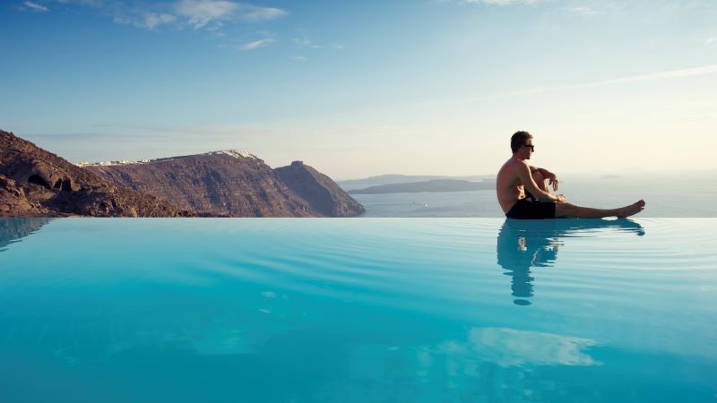man sitting on edge of infinity pool