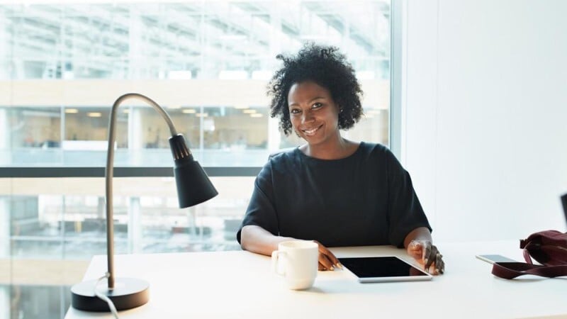 Woman smiling at desk with tablet