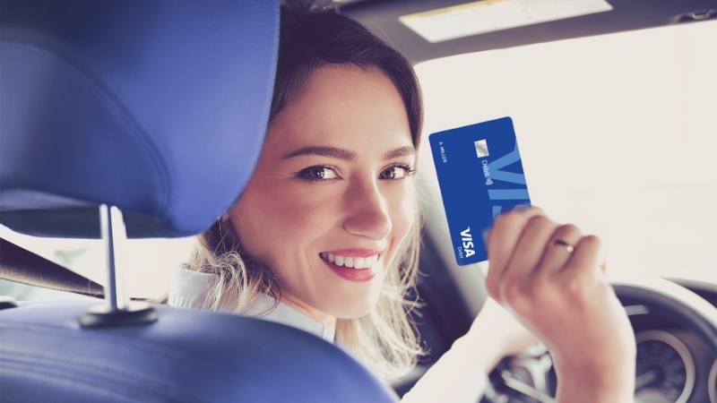 woman in car holding card