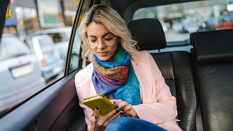 woman using mobile in back of taxi