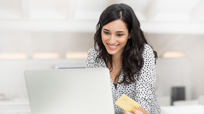 Woman in polka dots smiling at laptop